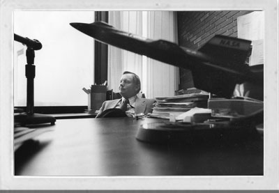 Armstrong at his UC desk in 1979, behind a model NASA aircraft.